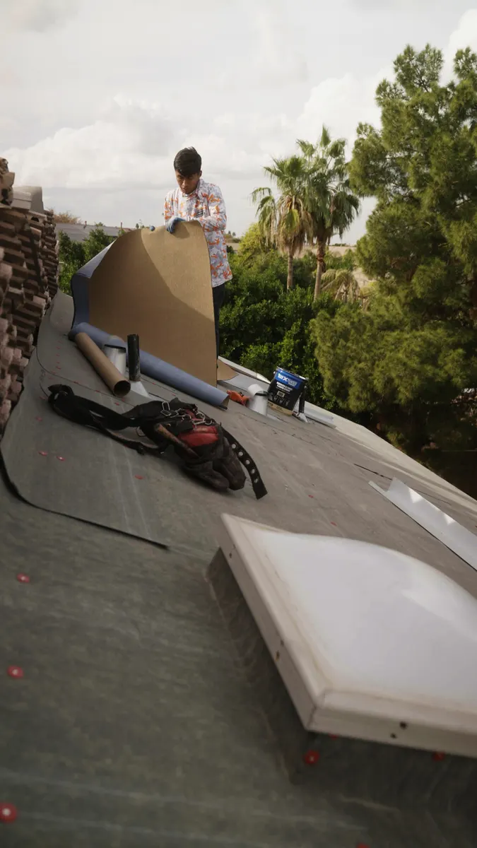 New underlayment going down on a tile roof, with tools, underlayment rolls and a skylight